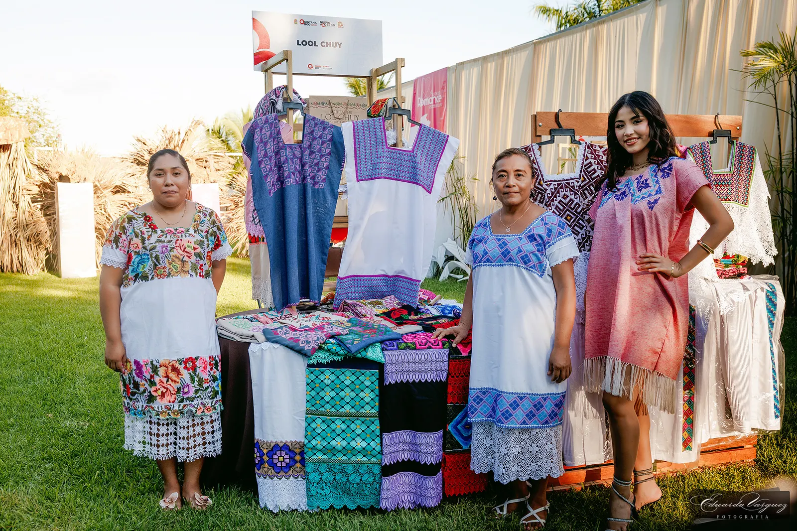 Artesanas mayas junto a su exhibición de huipiles y textiles bordados